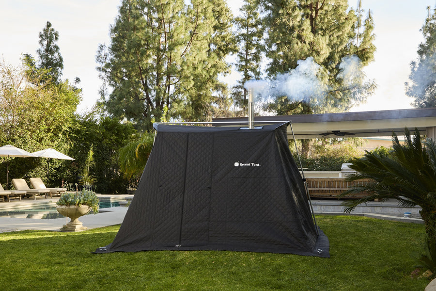 Sweat Tent XL portable sauna set up outdoors on grass with the chimney venting smoke