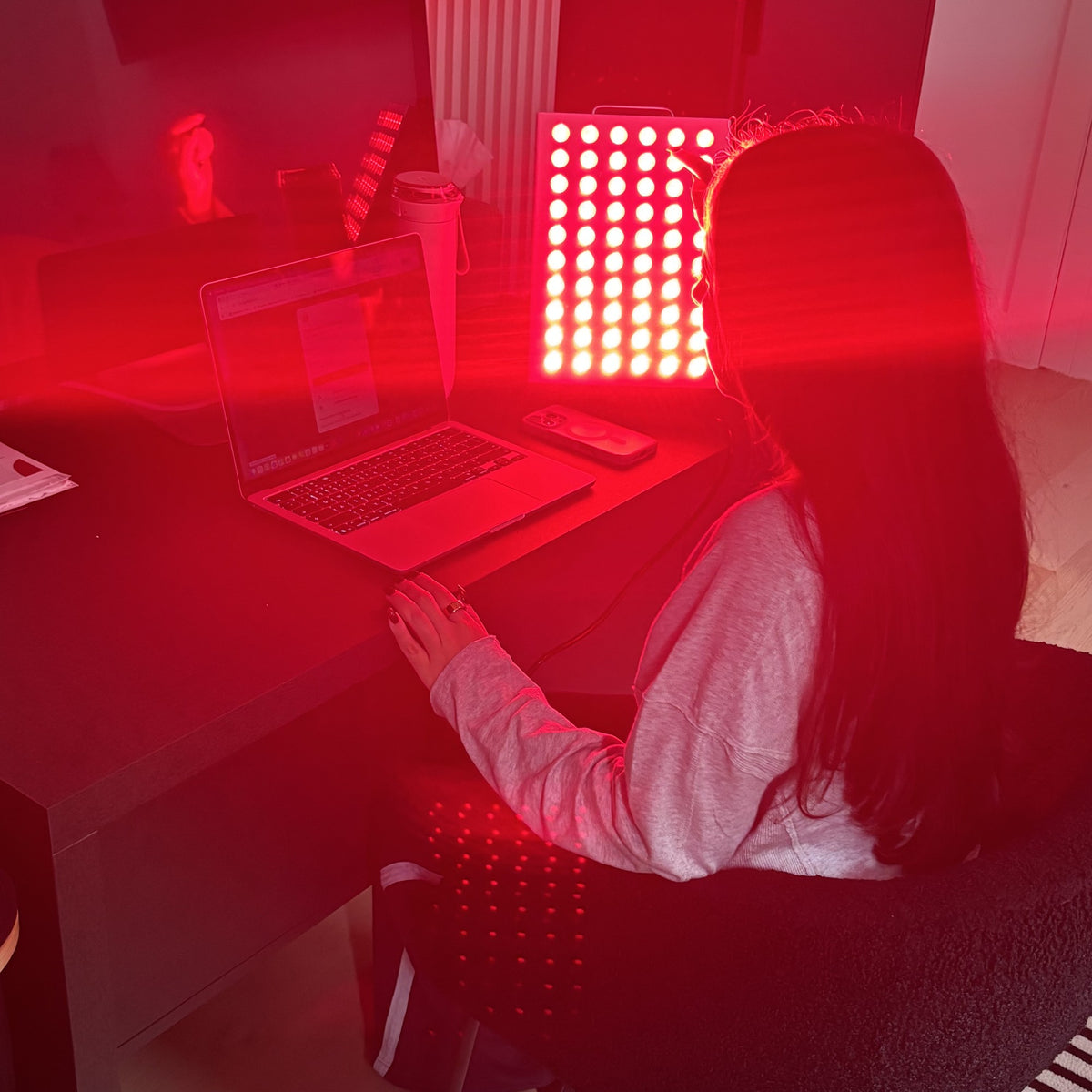 SunPanel Mini red light panel, lit on a desk